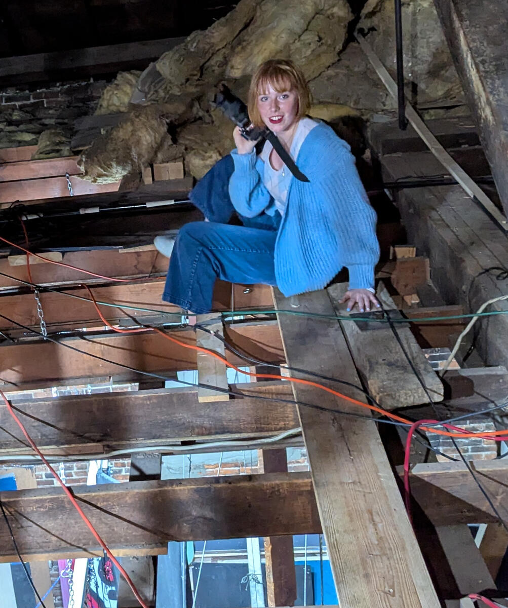 Bethany Nicole Muir taking load-in photos in the rafters for Clue: On Stage at MRT 2025