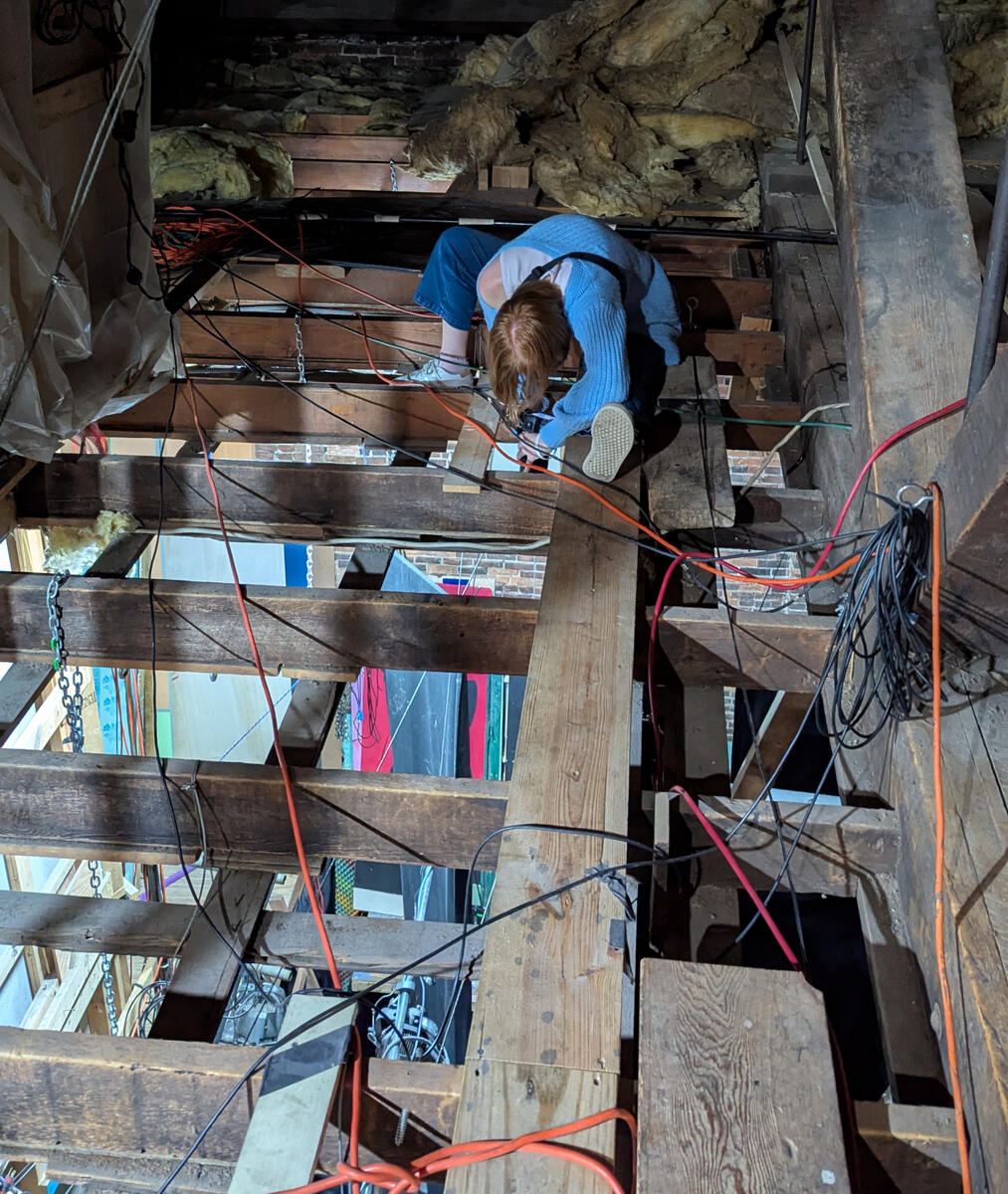 Bethany Nicole Muir taking load-in photos in the rafters for Clue: On Stage at MRT 2025
