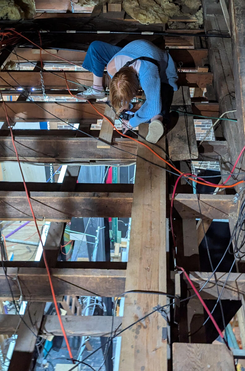Bethany Nicole Muir taking load-in photos in the rafters for Clue: On Stage at MRT 2025